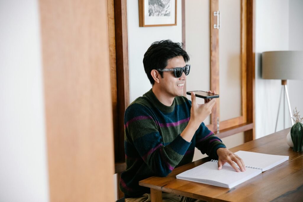 Smiling man with sunglasses using smartphone for conversation at home.